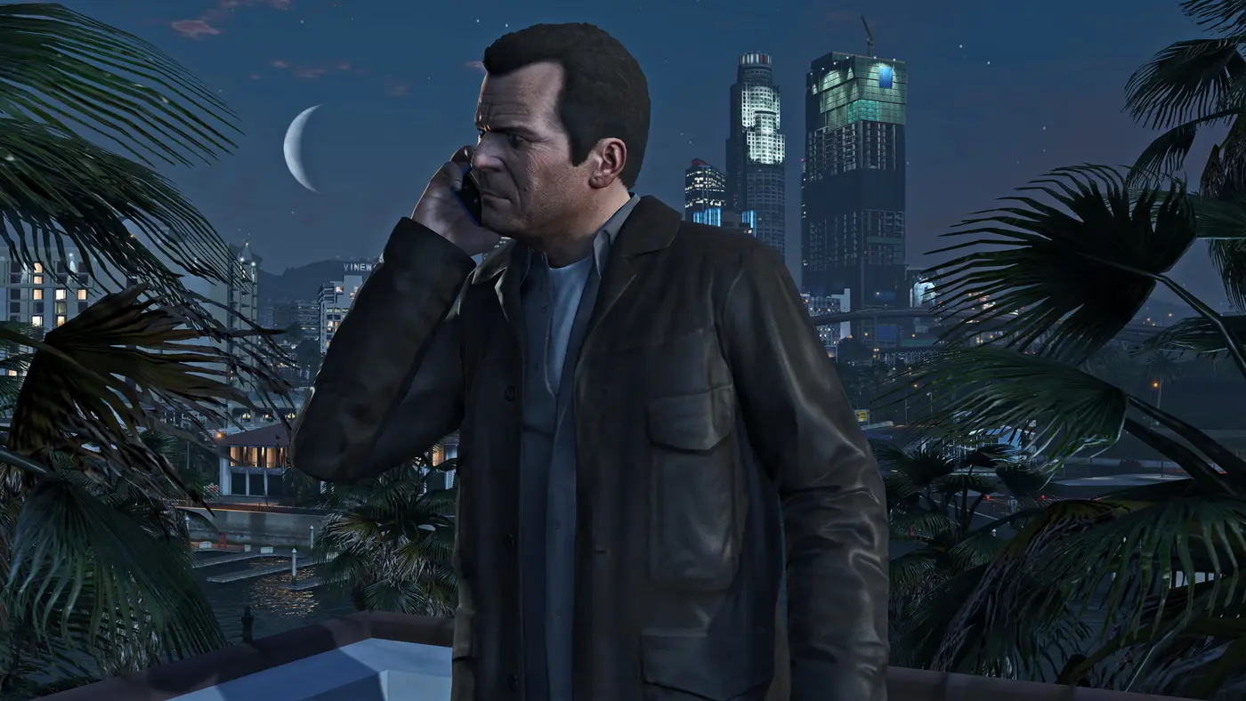 Michael on the phone at night in front of the Los Santos skyline, in GTA 5