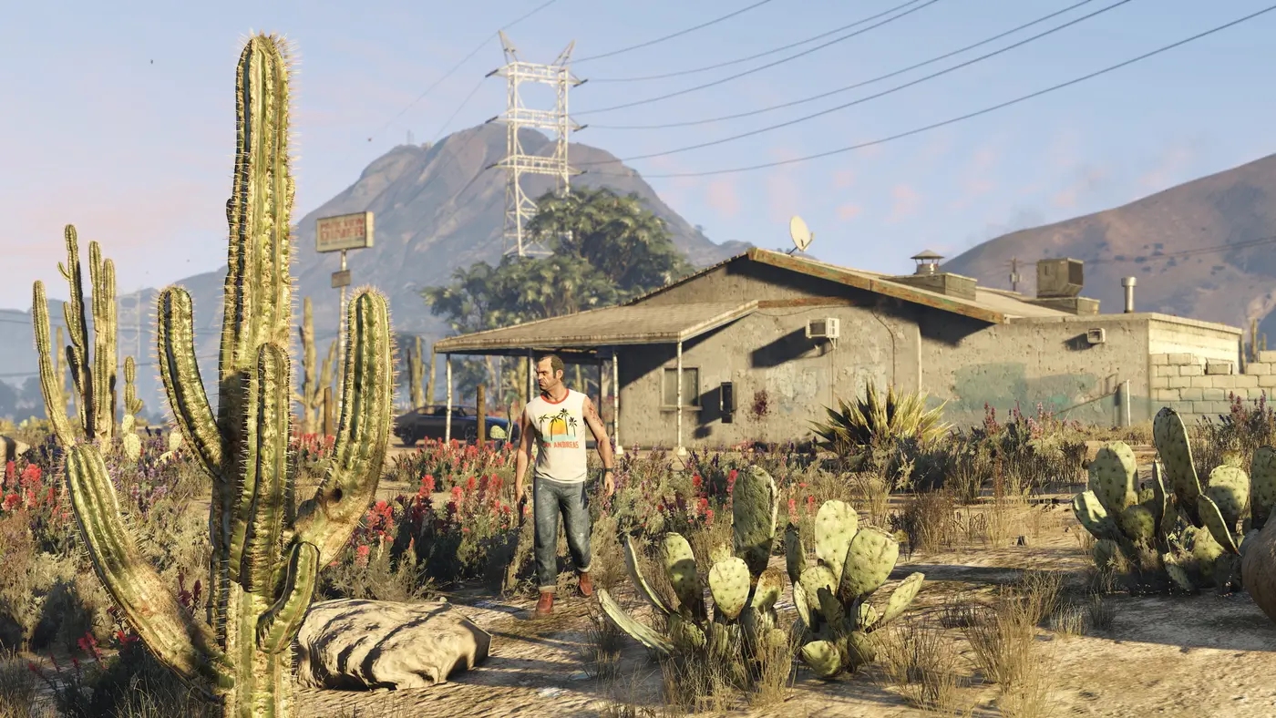 Trevor Philips walking through the Blaine County desert in front of a shack, in GTA 5