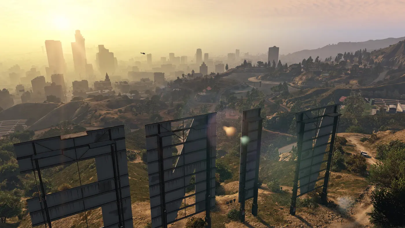 The back of the giant Vinewood sign on a hillside, overlooking the downtown Los Santos skyline in a golden haze