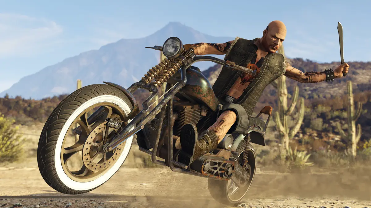 A bald, tattooed biker in a leather vest rides a rusty chopper through the desert, raising a machete, with a mountain in the background