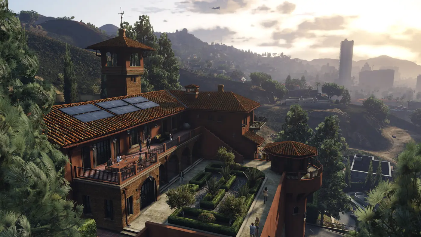 Aerial view of a Vinewood Hills mansion surrounded by hills, overlooking the Los Santos skyline in sunset light