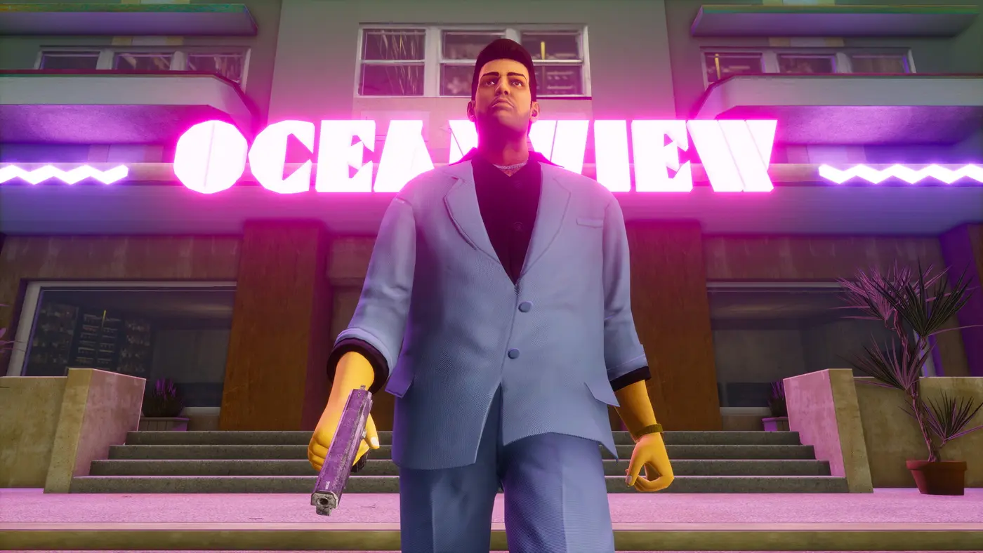 Tommy Vercetti in a pastel suit, pistol in hand, walking out of the pink neon-lit Ocean View hotel in GTA Vice City The Definitive Edition