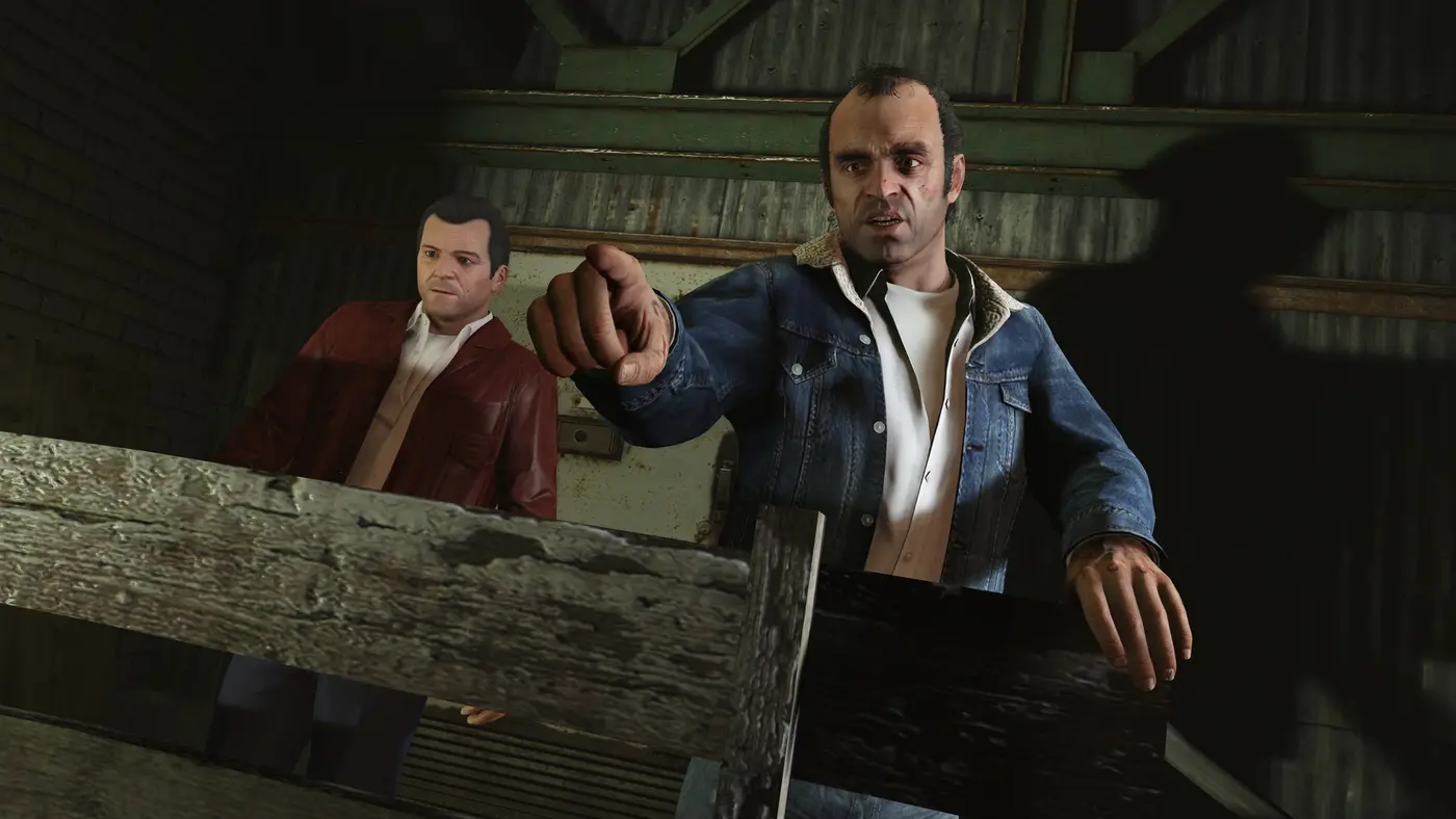 Michael De Santa in a red leather jacket on the left and Trevor Philips in a denim jacket pointing on the right, in a GTA V hangar