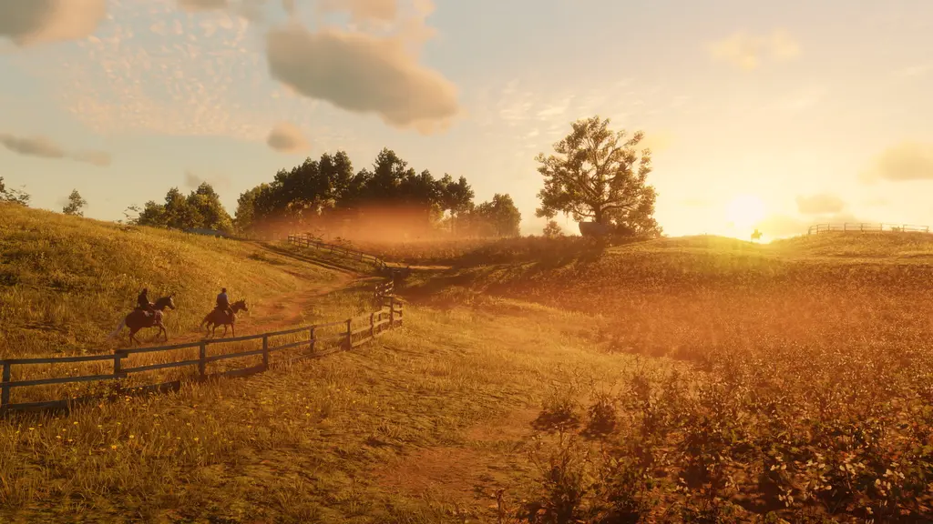 Two riders follow a wooden fence across grassy hills bathed in the golden light of the setting sun in Red Dead Redemption 2