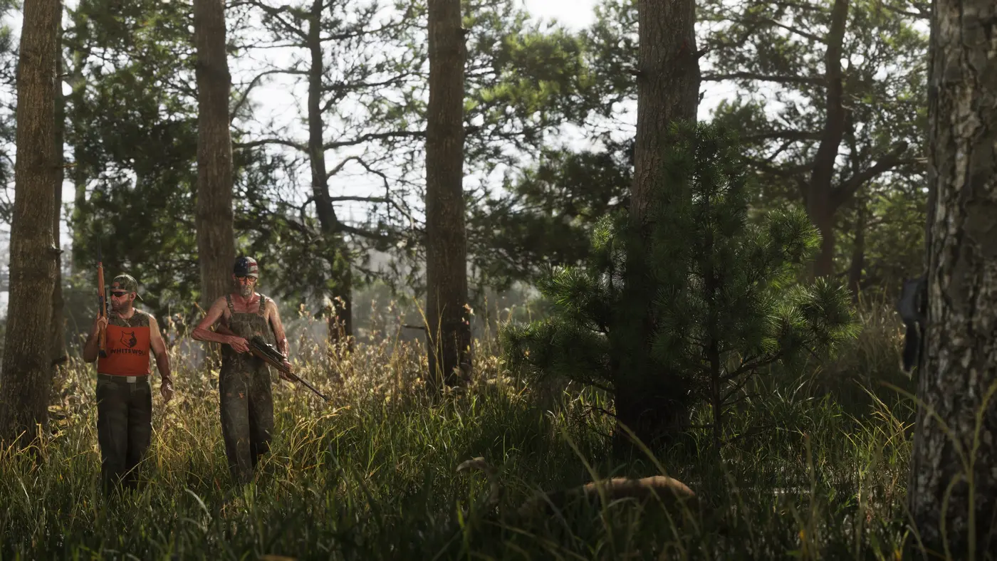 Two park rangers in orange vests walking through the tall grass of a pine forest in Mount Kalaga National Park